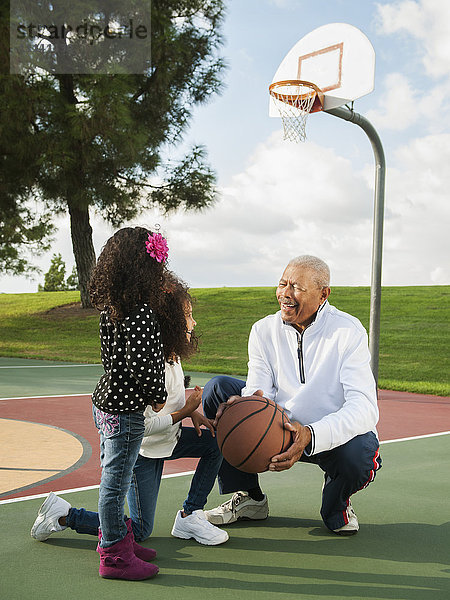 Mann spielt Basketball mit Enkeltöchtern