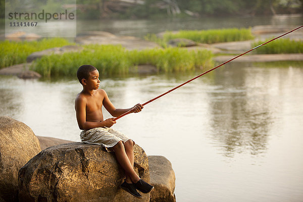 Afroamerikanischer Junge beim Fischen im See