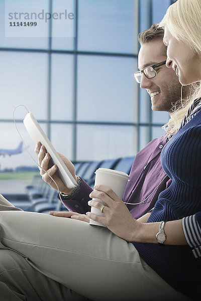 Kaukasisches Paar benutzt digitales Tablet im Flughafen