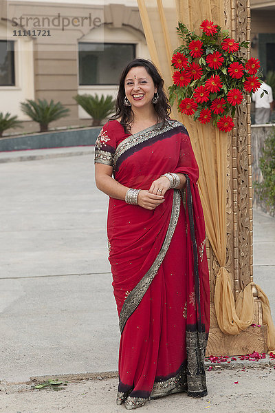 Lächelnde gemischtrassige Frau in indischer Kleidung