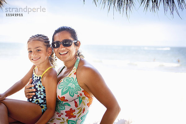 Lächelnde Mutter und Tochter genießen den tropischen Strand