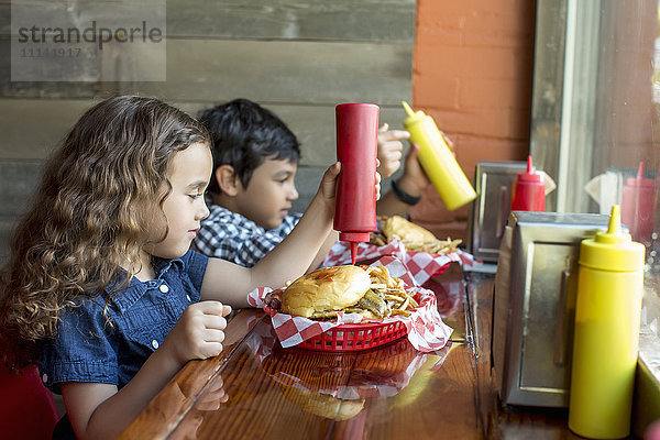 Gemischtrassige Kinder essen Burger im Restaurant