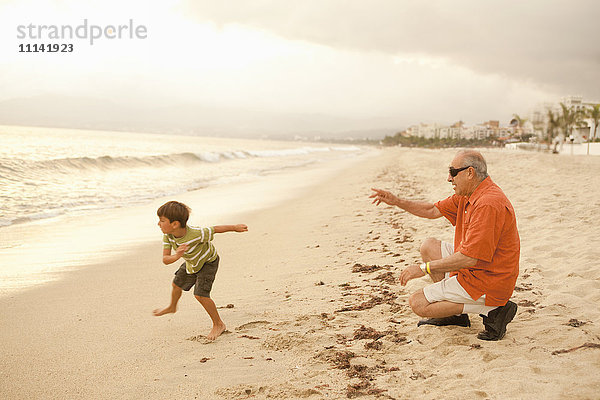 Großvater und Enkelsohn spielen zusammen am Strand