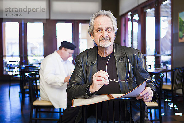 Weißer Mann hält Speisekarte im Restaurant