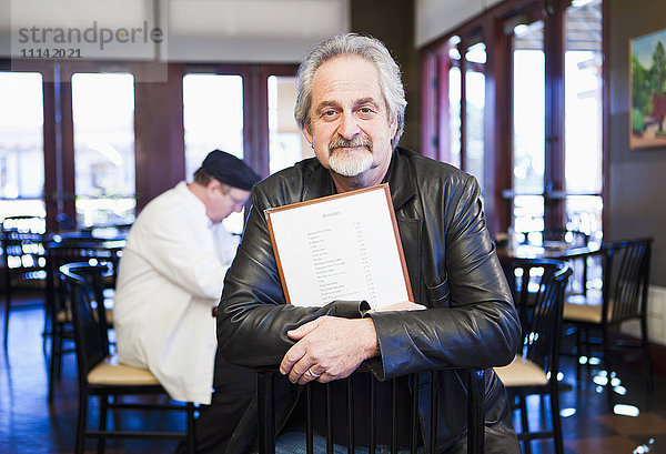 Weißer Mann hält Speisekarte im Restaurant