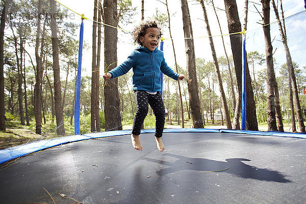 Gemischtrassiges Mädchen springt auf Trampolin