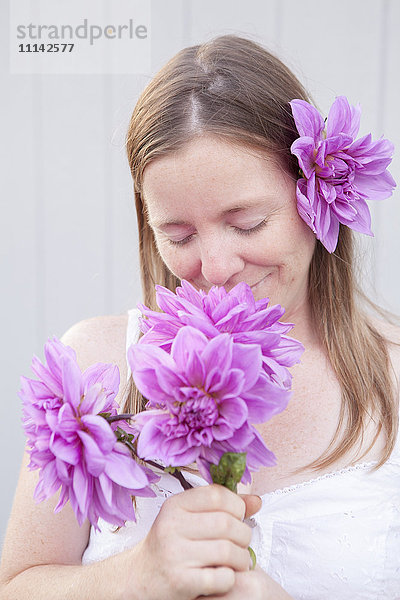 Gemischtrassige Frau riecht an Blumen