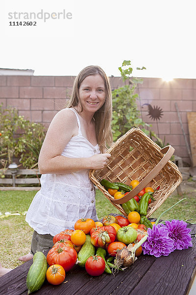 Gemischtrassige Frau mit Korb mit Gemüse und Blumen