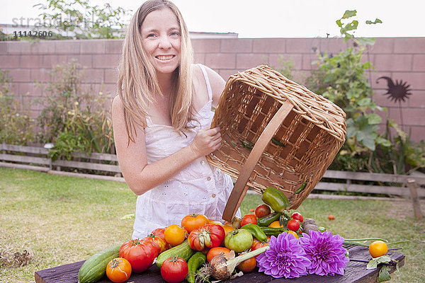 Gemischtrassige Frau mit Korb mit Gemüse und Blumen