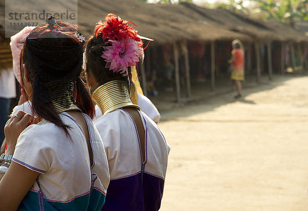 Studenten tragen traditionellen Schmuck in der Nähe von Hütten