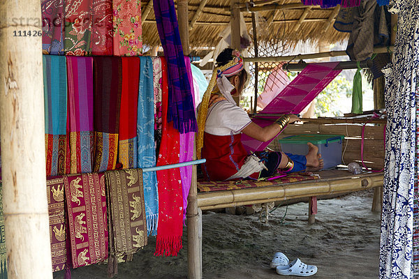 Frau beim Weben von Stoffen auf einem traditionellen Webstuhl im Atelier
