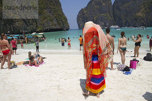 Frau mit traditionellem Kopftuch steht am Strand