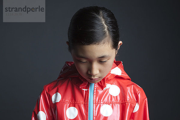 Trauriges asiatisches Mädchen mit Regenmantel
