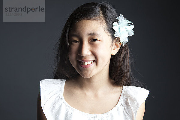 Lächelndes asiatisches Mädchen mit Blume im Haar
