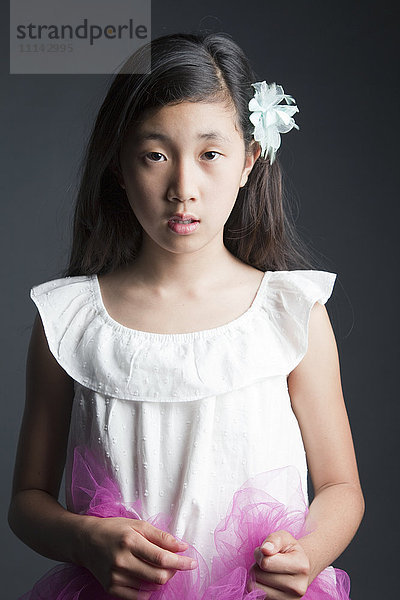 Seriöses asiatisches Mädchen mit Blume im Haar
