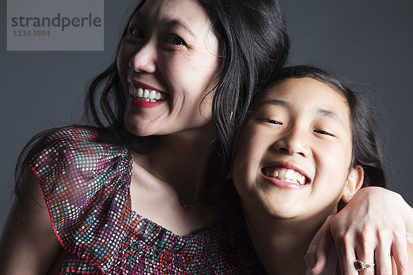 Lächelnde asiatische Mutter und Tochter umarmen sich