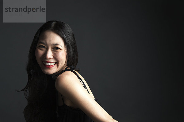 Asiatische Frau lächelt über ihre Schulter