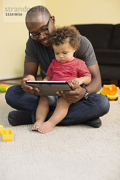 Vater und Sohn im Kleinkindalter benutzen ein digitales Tablet