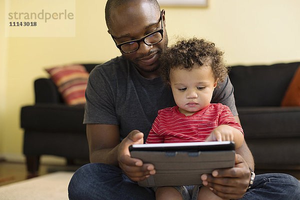 Vater und Kleinkind benutzen digitales Tablet