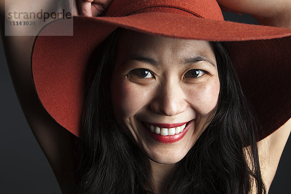 Lächelnde asiatische Frau mit rotem Hut