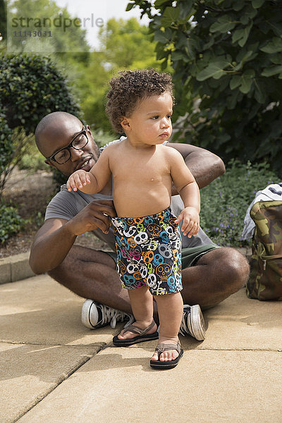 Vater passt die Shorts seines Kleinkindes im Park an