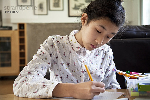 Nahaufnahme eines asiatischen Teenagers bei den Hausaufgaben