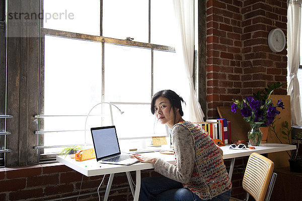 Taiwanesische Frau benutzt Laptop im Heimbüro