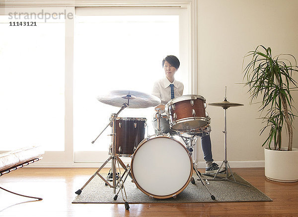 Japanische Frau spielt Schlagzeug im Wohnzimmer