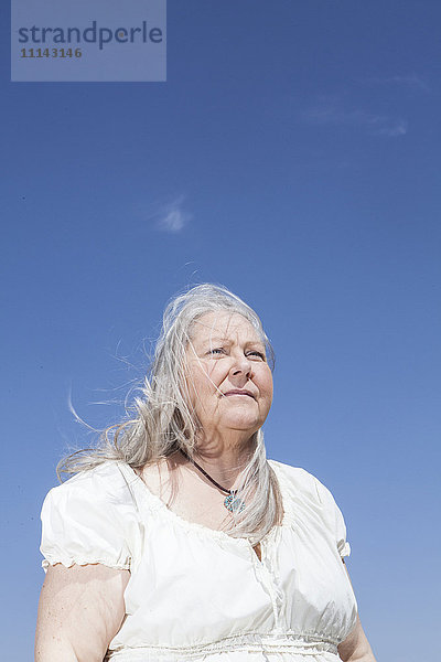 Kaukasische Frau steht unter blauem Himmel