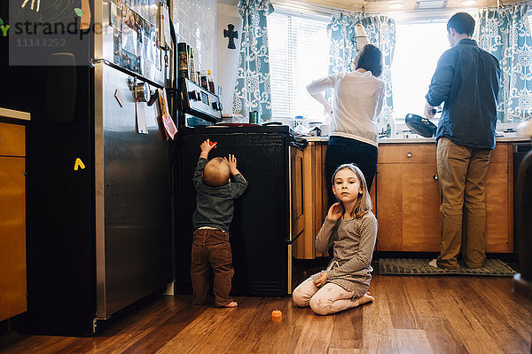 Kinder spielen  während die Eltern in der Küche kochen
