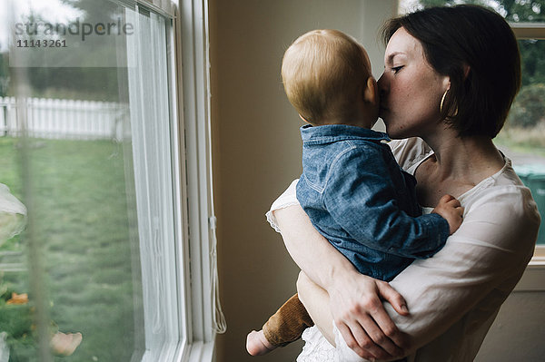 Mutter küsst Sohn am Fenster