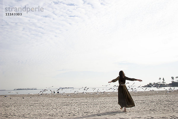 Frau im Kleid spielt am Strand