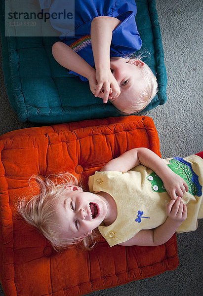 Bruder und Schwester spielen auf Kissen auf dem Boden