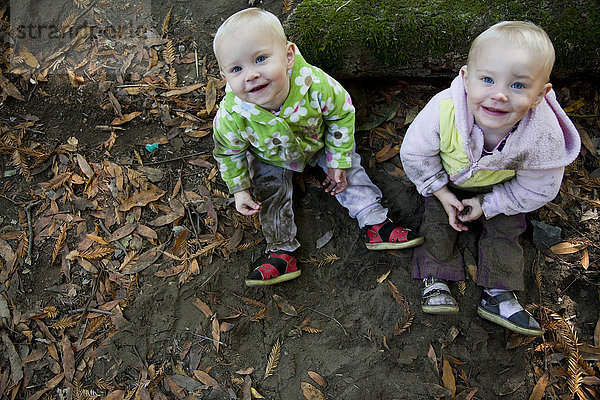 Lächelnde Kinder auf dem Waldboden