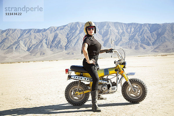 Frau auf Motorrad in der Wüste stehend