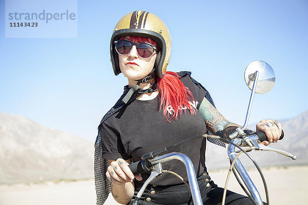 Frau auf Motorrad in der Wüste sitzend