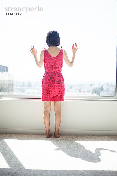 Asiatische Frau schaut aus dem Fenster