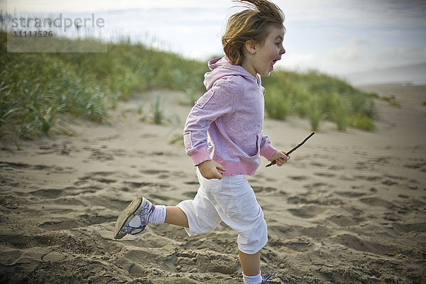Verspieltes Mädchen läuft am Strand