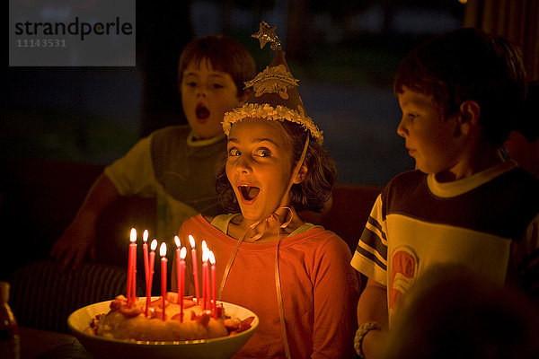Lachendes Mädchen  das Kerzen auf einem Geburtstagskuchen ausbläst