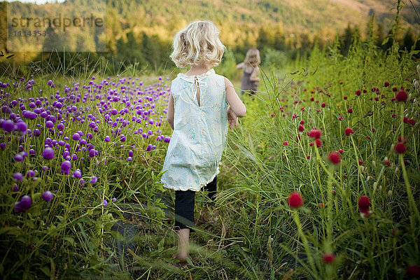 Mädchen  das in einem ländlichen Blumenfeld spazieren geht