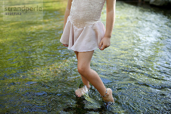 Mädchen steht barfuß im Teich