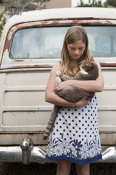 Mädchen hält Katze in der Nähe von Oldtimer