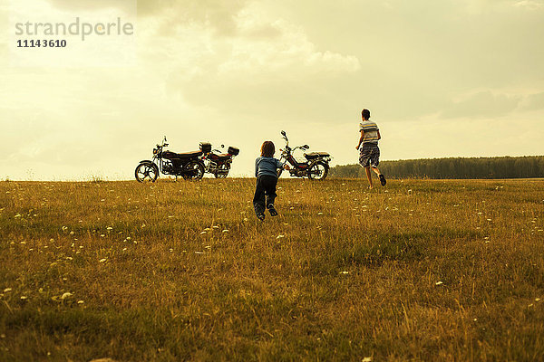 Jungen laufen zu Motorrädern in ländlicher Landschaft