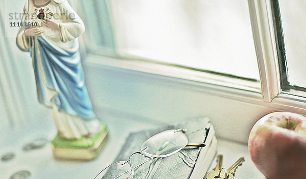 Nahaufnahme von Gläsern  religiöser Statue und Obst auf der Fensterbank