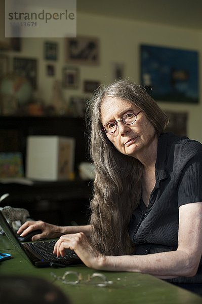 Ältere Frau mit Laptop am Schreibtisch