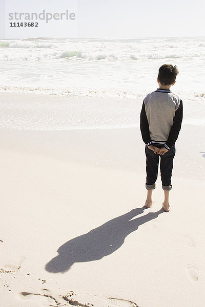 Junge steht am sonnigen Strand
