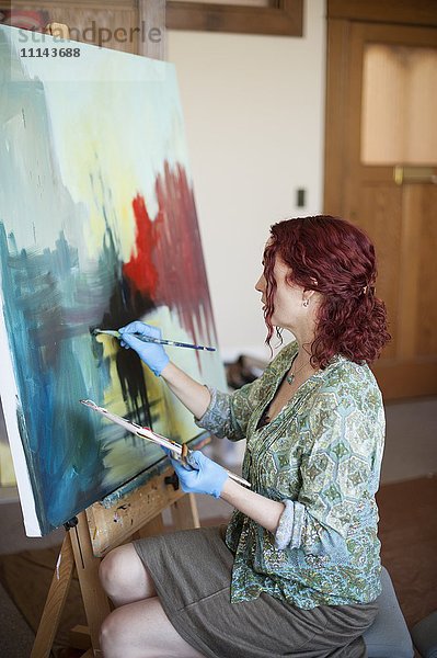 Künstlerin malt im Atelier auf Leinwand