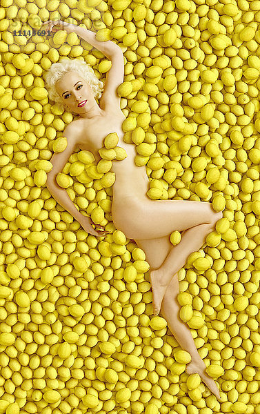 Kaukasische Frau liegt in einem Haufen Zitronen