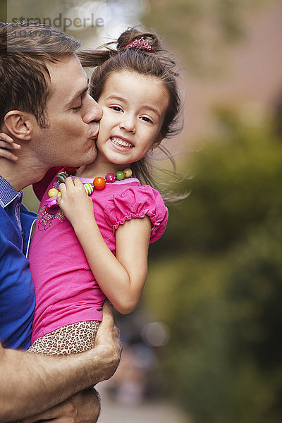 Vater küsst Tochter auf der Straße in der Stadt