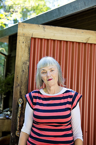 Ältere kaukasische Frau steht im Hinterhof